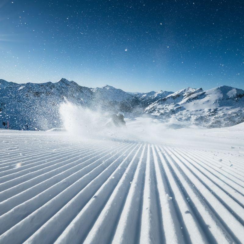 Skifahrer auf frisch präparierter Piste in den Alpen bei Sonnenschein